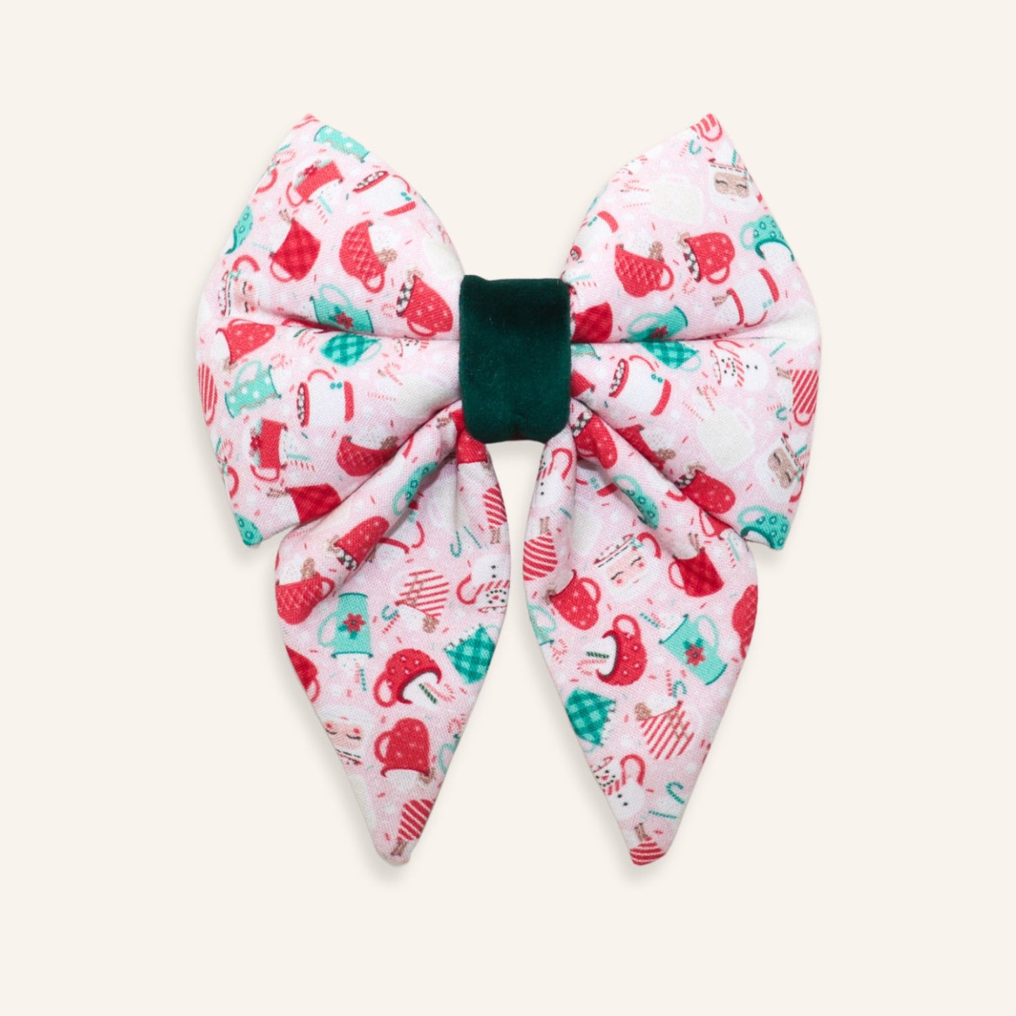 Handmade pink Christmas dog sailor bow featuring festive mugs, mittens, Santa hats, candy canes, and holiday icons with a deep green velvet center, designed to slide onto a dog collar.
