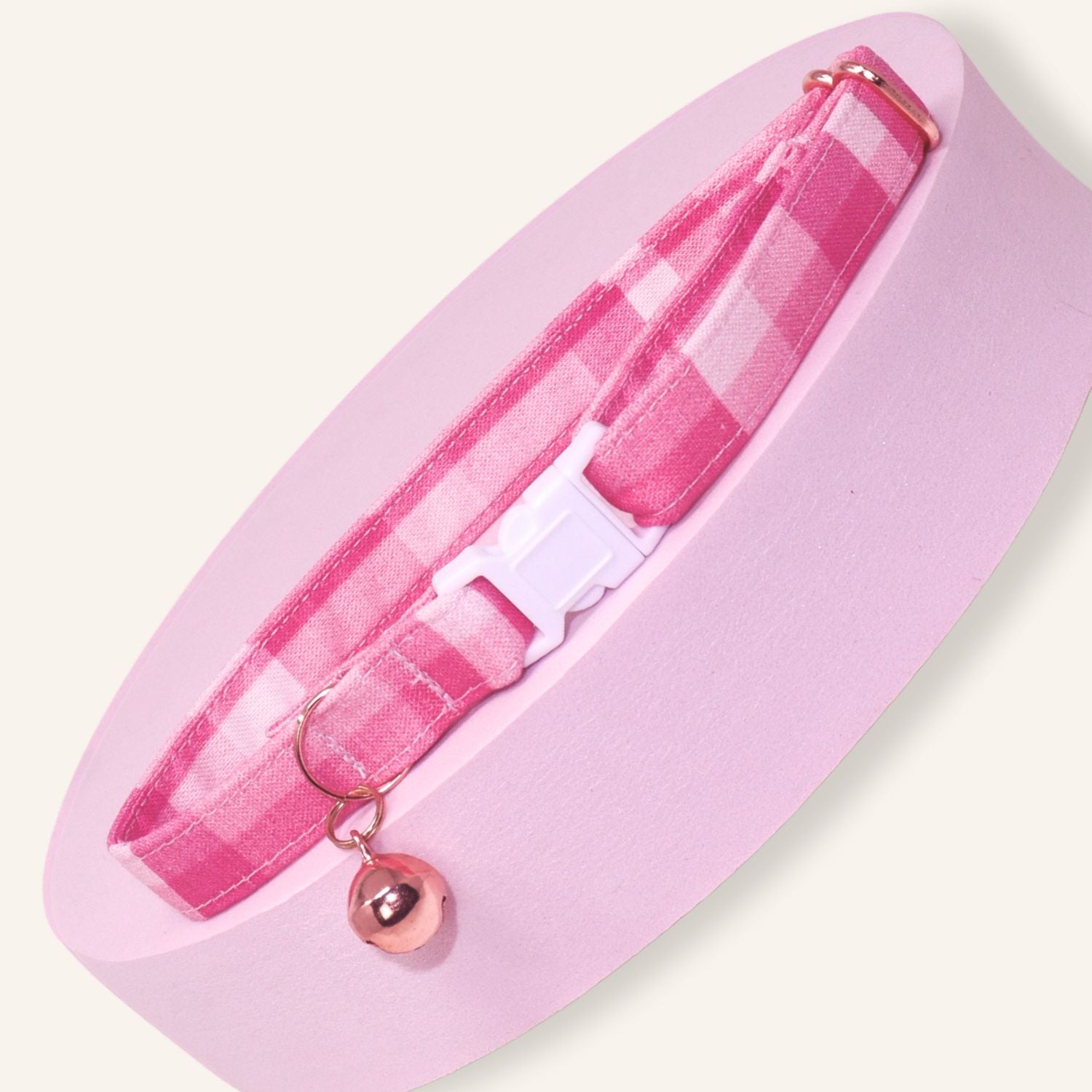 Handmade pink gingham breakaway cat collar featuring a classic buffalo check pattern, white safety buckle, rose gold bell, and adjustable cotton design for kittens and adult cats.