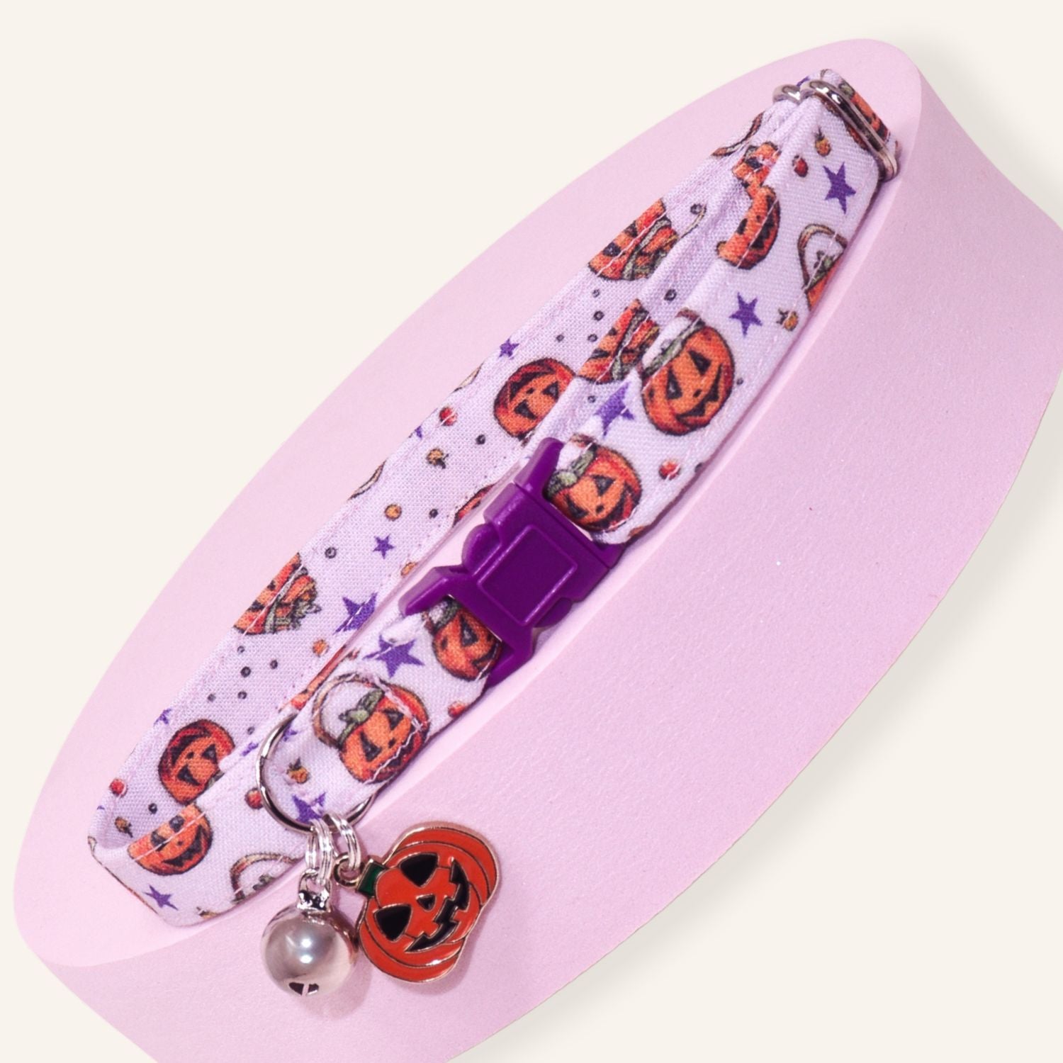 Handmade Halloween pumpkin breakaway cat collar featuring jack-o'-lanterns, purple safety buckle, silver bell, and pumpkin charm for kittens and adult cats.