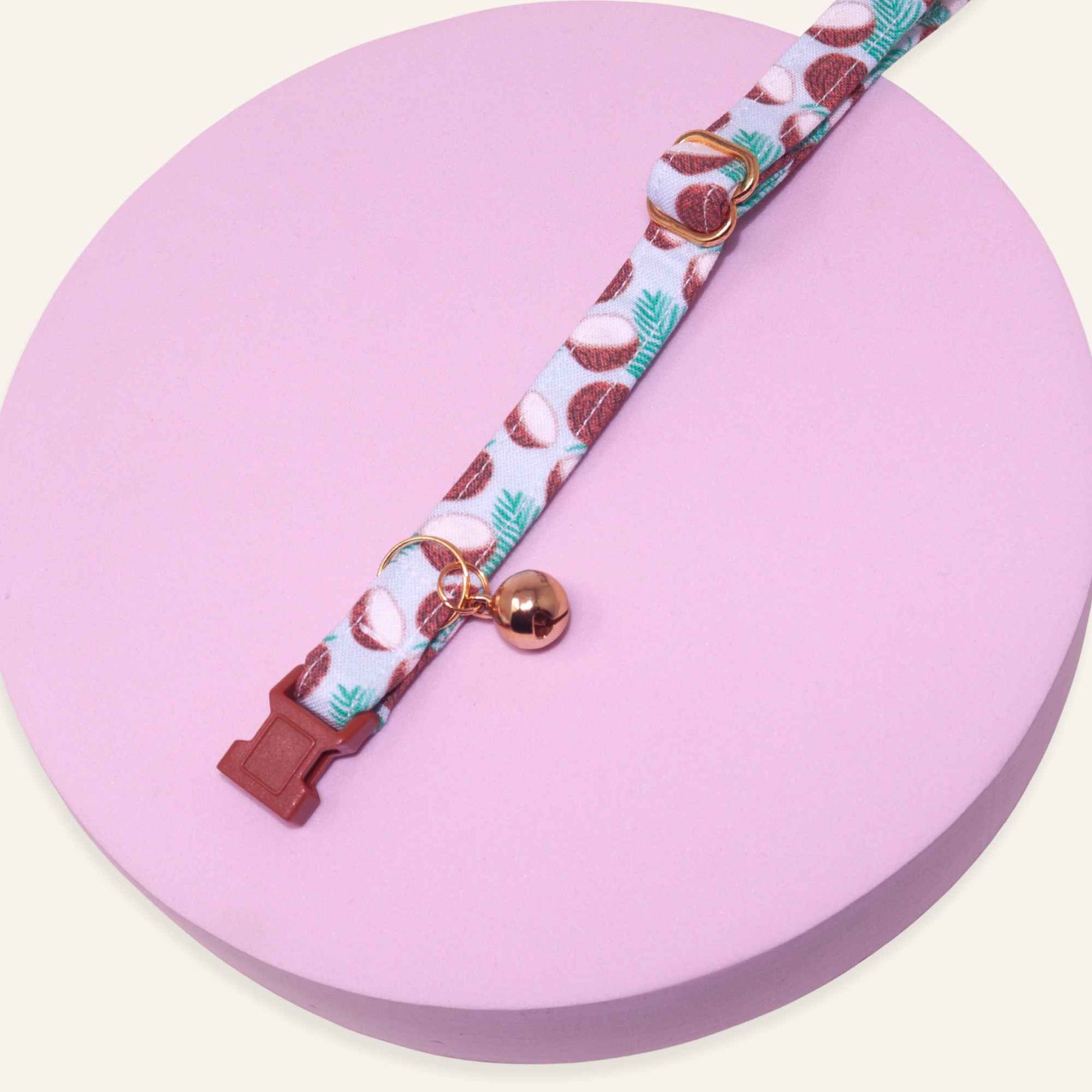 Tropical coconut and palm leaf breakaway cat collar with gold hardware, adjustable fit, safety buckle, and optional bell.