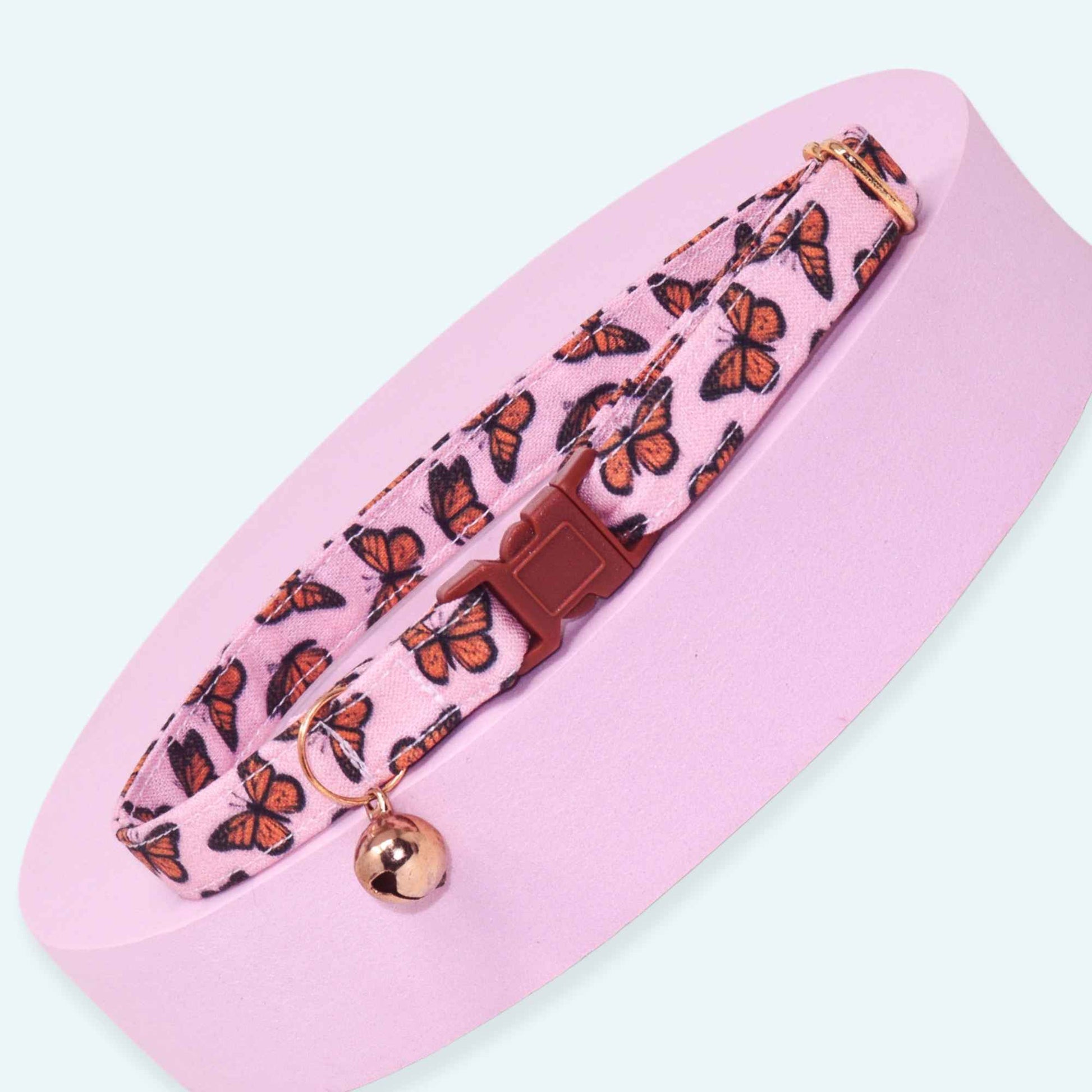 Pink breakaway cat collar featuring orange monarch butterflies, rose gold hardware, and an optional bell.