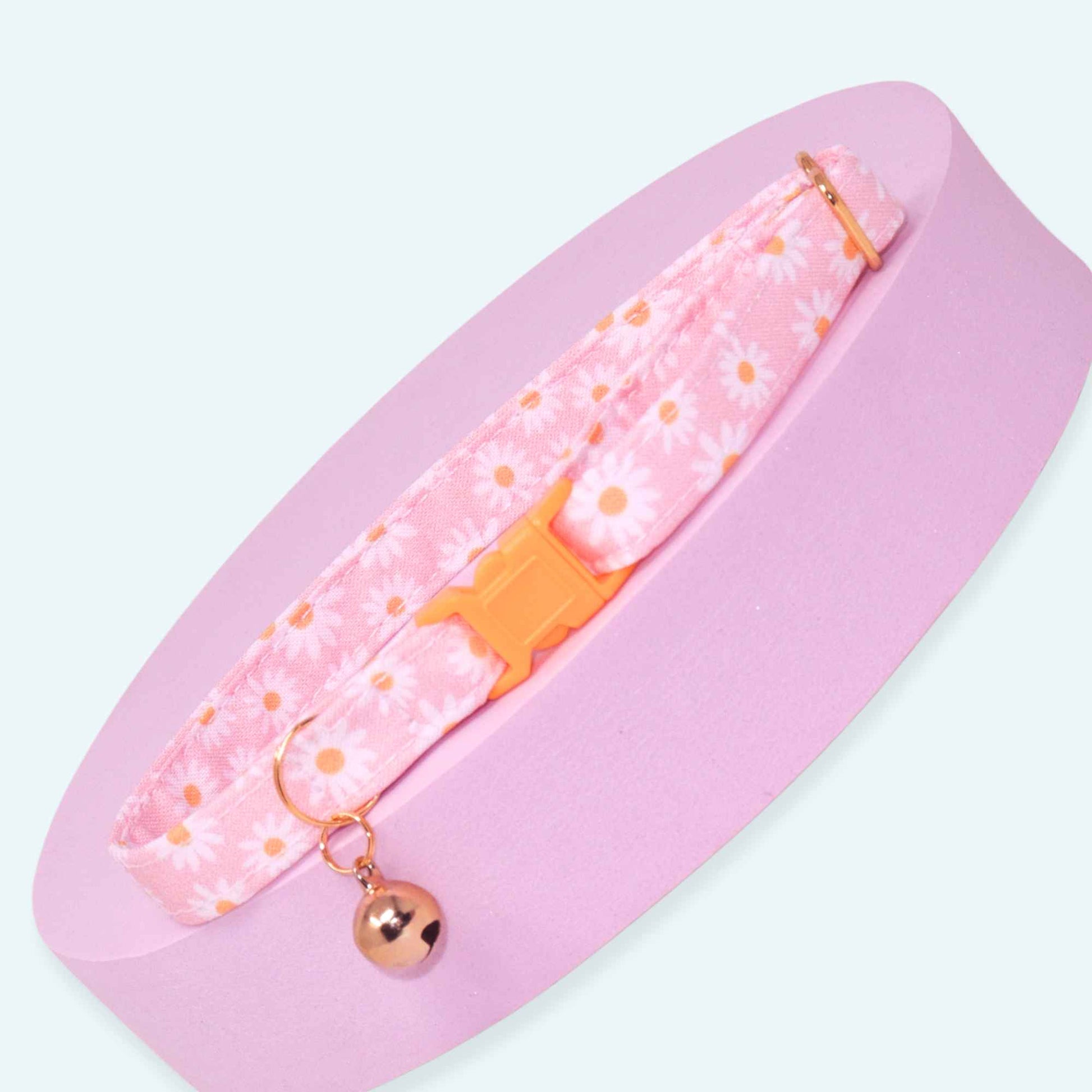 Pink breakaway cat collar with white daisy print, rose gold hardware, adjustable fit, and optional bell.