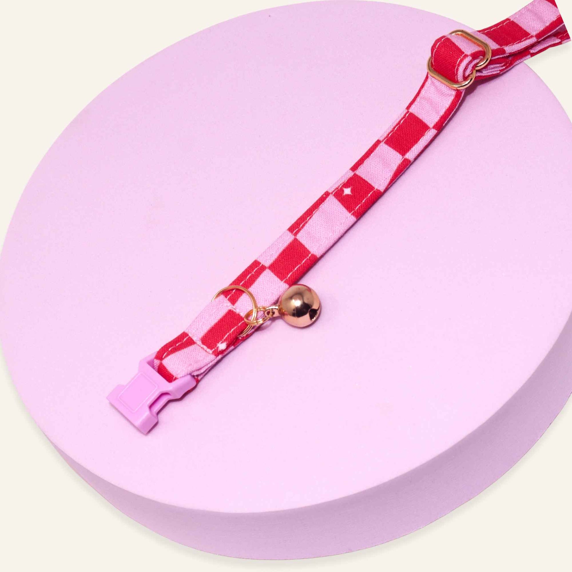 Adjustable pink groovy checkered cat collar featuring rose gold hardware and a pink breakaway buckle.